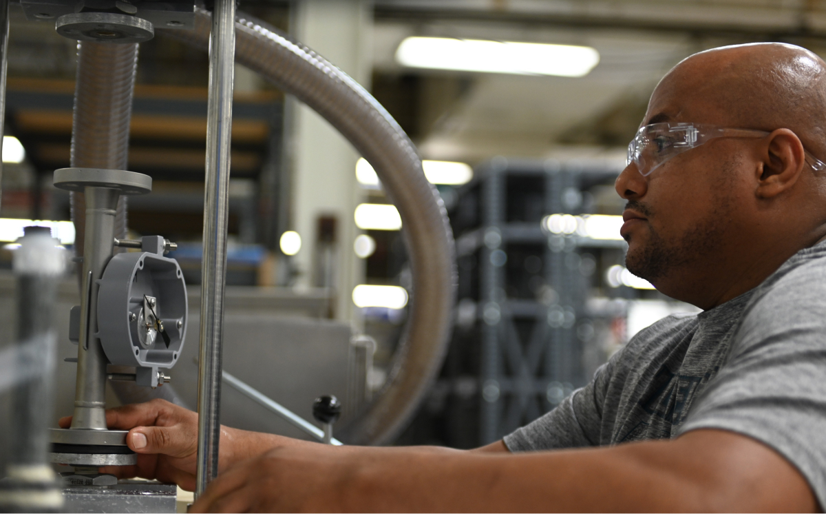 A man in a gray shirt operates a machine, representing a career at Brooks Instrument.
