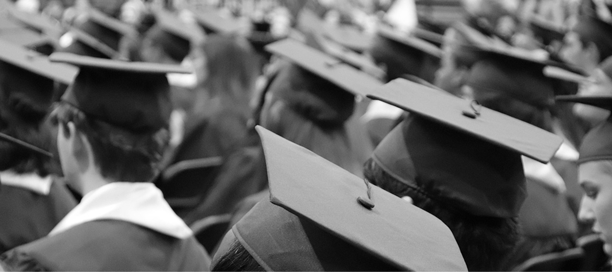 A group of graduates in caps and gowns gathers at a graduation ceremony, symbolizing their academic accomplishments.