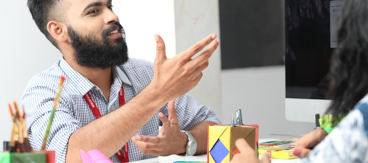 A bearded man in glasses converses with another person, both engaged in a discussion.