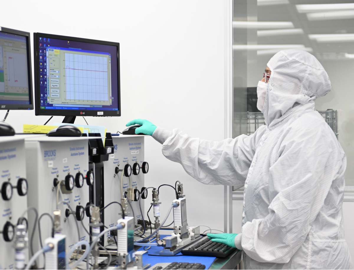 Brooks Instrument staff member in a lab coat, engaged in work within a laboratory space.